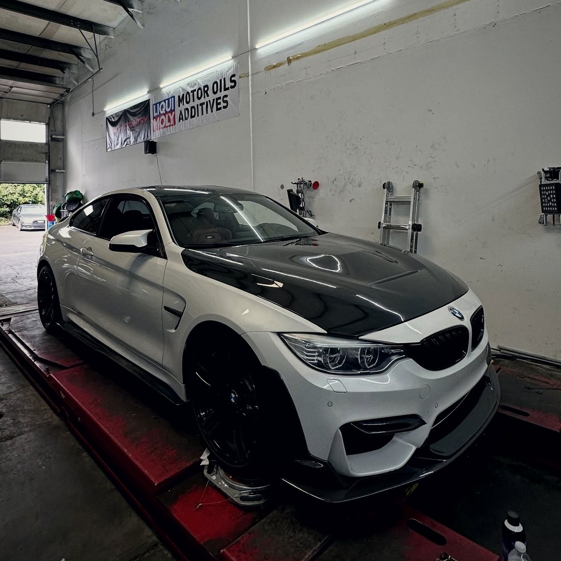 A dark performance sedan up in the shop
